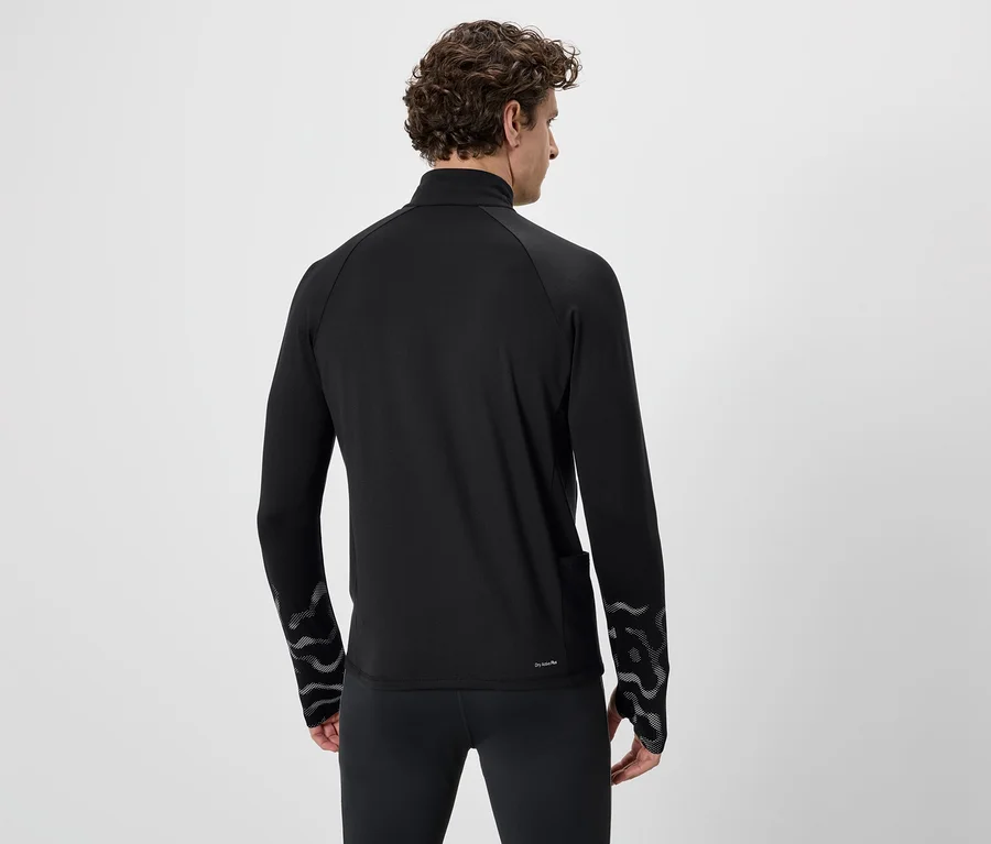 Von hinten ist ein Mann mit lockigem Haar in einem schwarzen Sportoberteil und Leggings zu sehen. Das Oberteil hat ein Muster an den Ärmeln.
