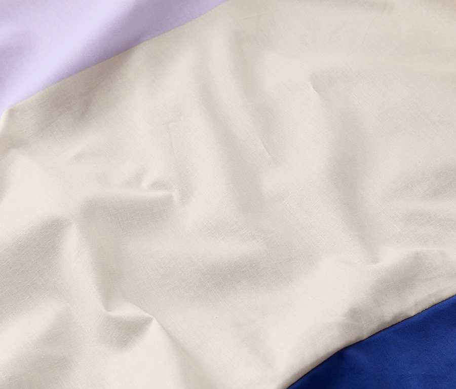 Nahaufnahme von drapiertem Stoff in Lila, Creme und Blau.