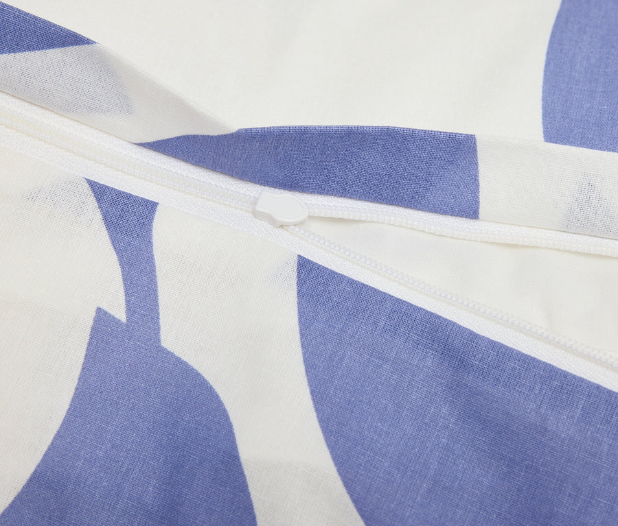 Nahaufnahme eines Reißverschlusses auf einem blau-weiß gemusterten Stoff.