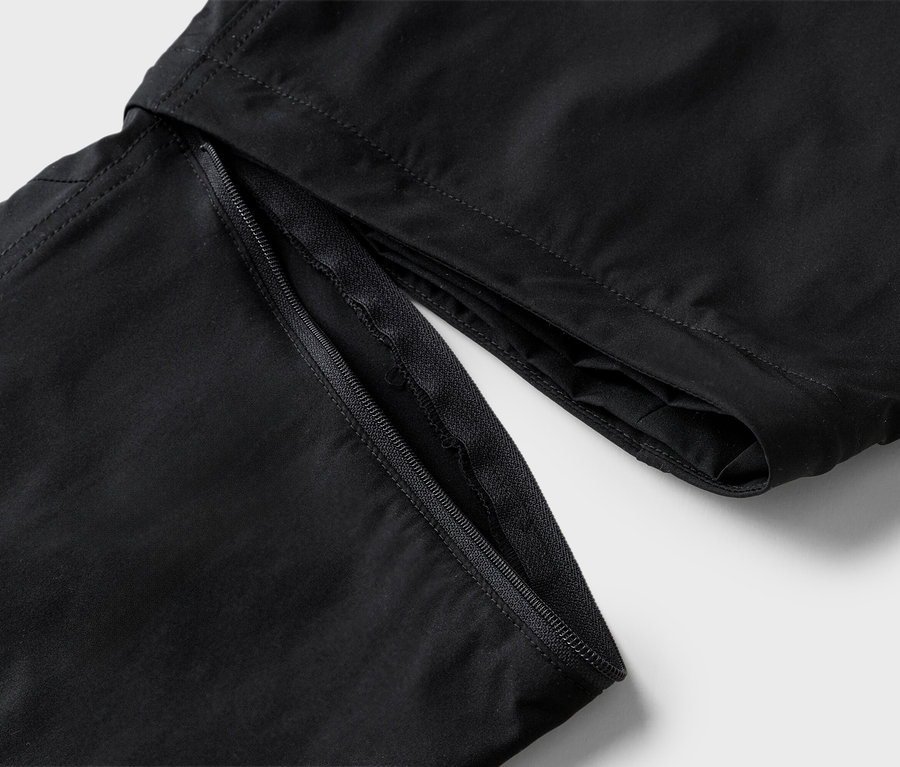 Detailansicht einer schwarzen Hose mit offenem Reißverschluss.
