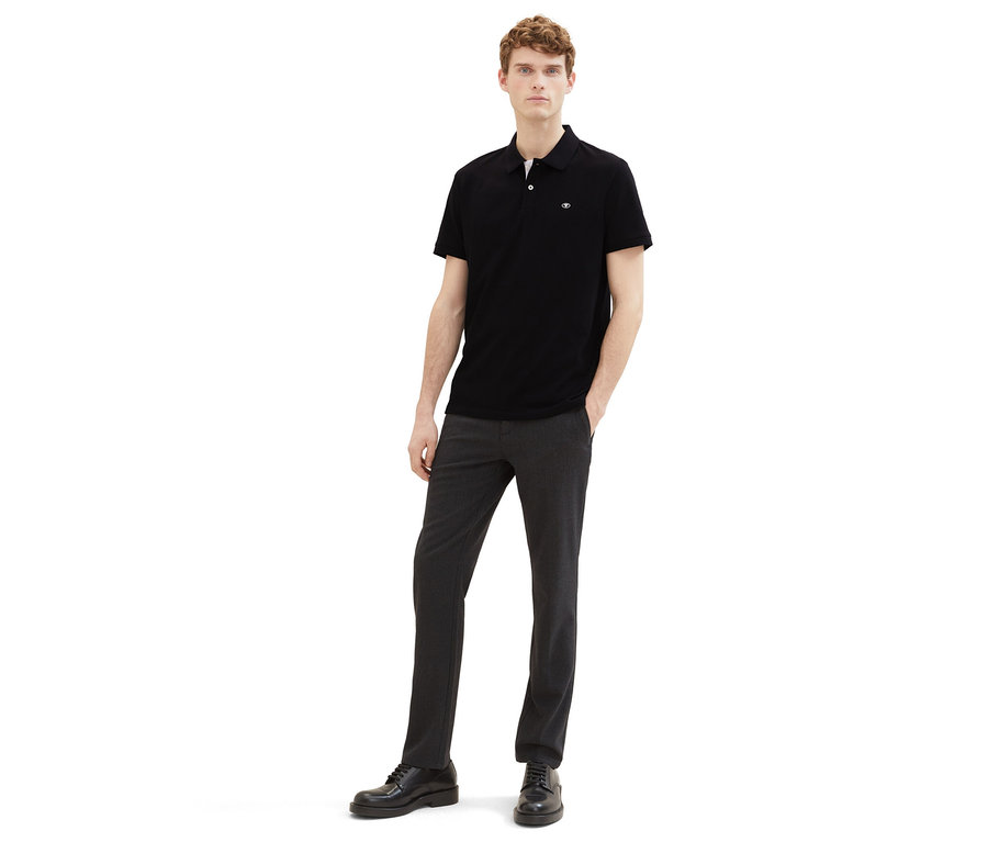 Mann in dunkler Hose und schwarzem Tom Tailor Piqué Poloshirt.