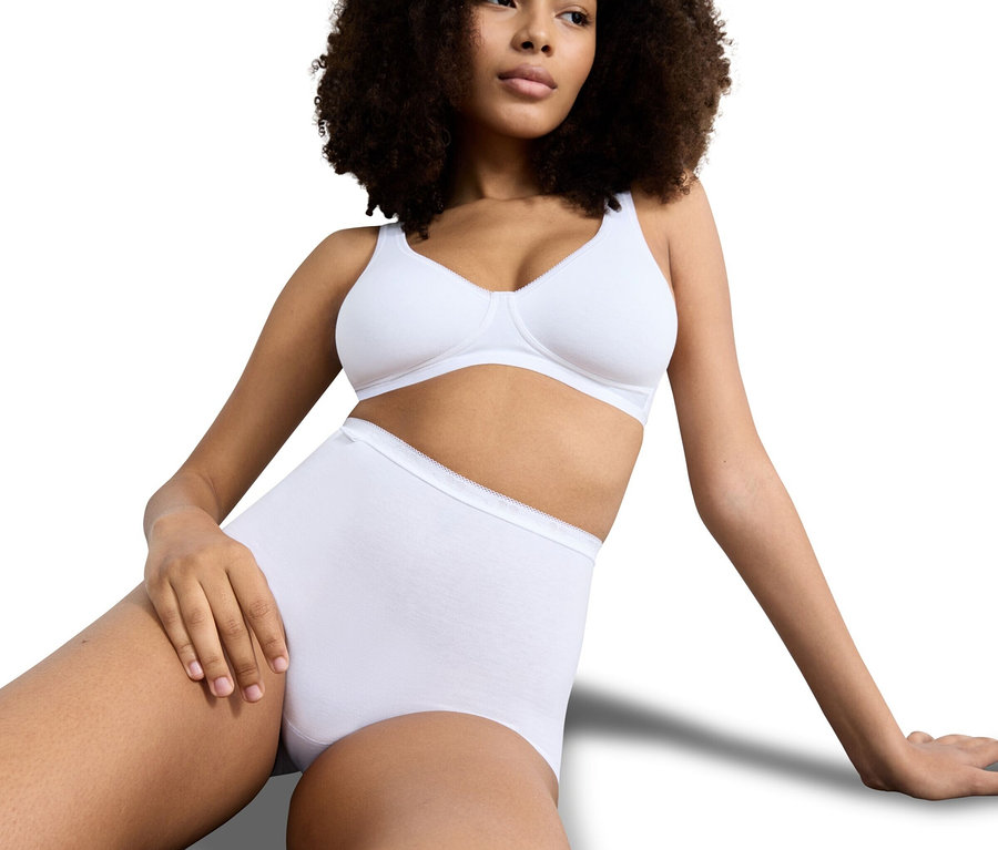 Frau mit Afro, die einen weißen BH und weißen Slip trägt.