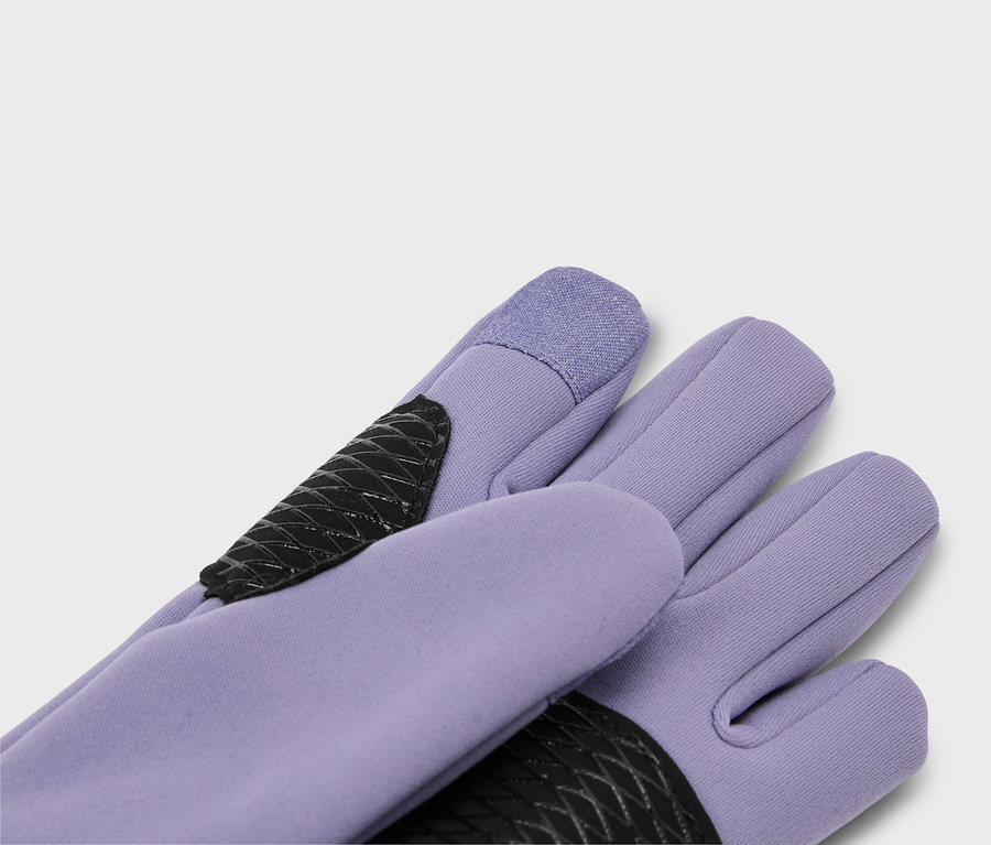 Nahaufnahme von lila Handschuhen mit schwarzen, rautenförmigen Verstärkungen und Touchscreen-kompatiblen Fingerspitzen.