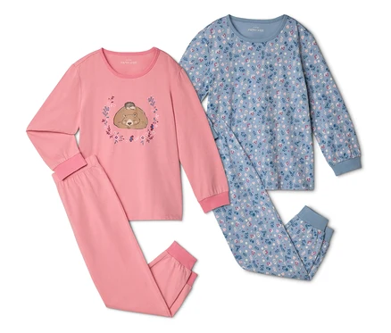 Zwei Schlafanzüge liegen nebeneinander, einer rosa mit Bär und Igel, der andere blau mit Blumenmuster.
