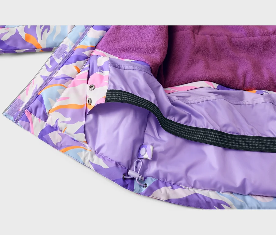 Bunte Jacke mit lila, pinken, orangen und hellblauen Mustern, innen helllila gefüttert. Sichtbar sind dunkellila Fleecefutter, ein schwarzer elastischer Schneefang und ein lila Kordelzug am Saum.