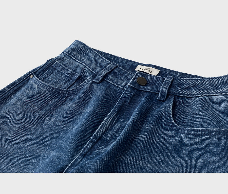 Blaue Jeans aus Denim, Nahaufnahme des oberen Vorderteils mit Vordertaschen, Münztasche, Gürtelschlaufen, einem schwarzen Knopf und einem weißen „MYSTYLE“-Etikett.