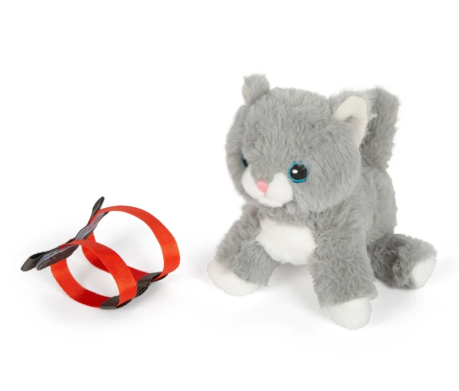 Eine graue small foot Stoffkatze mit Tasche und Pflege-Set liegt neben einer orangefarbenen Leine.