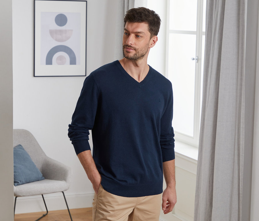 Mann posiert in marineblauem Leinen-Pullover.