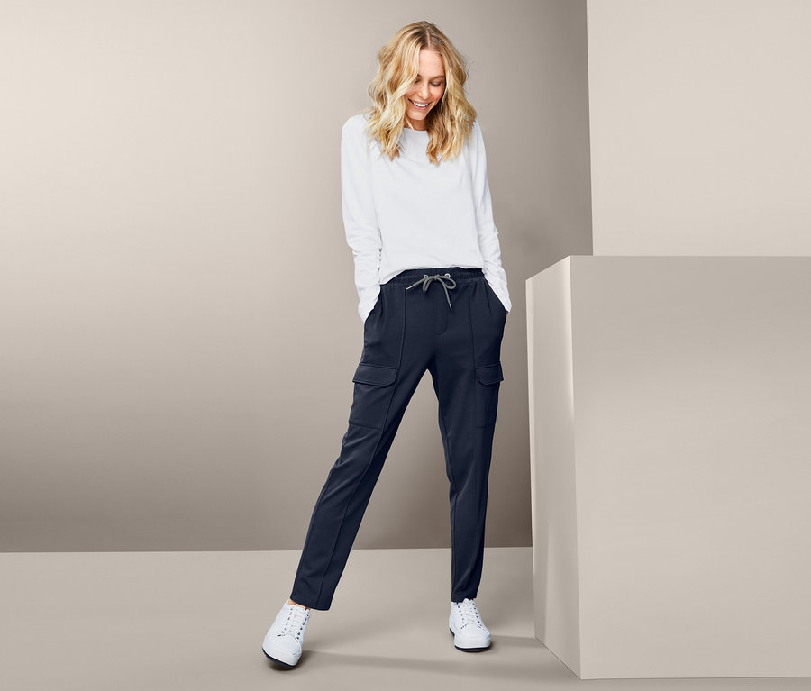 Frau trägt ein weißes Oberteil und eine dunkelblaue Joggpants mit Cargo-Taschen.
