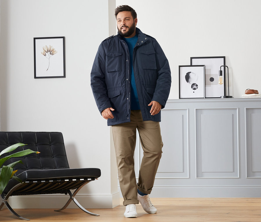 Mann trägt eine blaue Fieldjacket, einen blauen Merino-Pullover, eine camelfarbene Chino und dunkelblaue, rote und dunkelgrüne Merino-Socken.