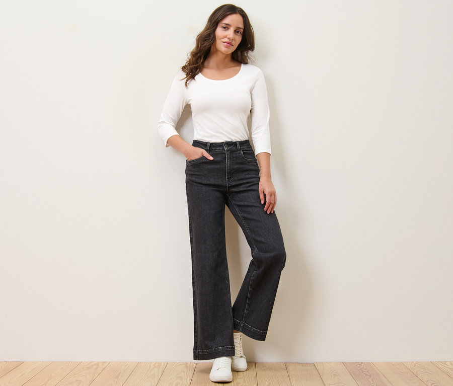 Frau posiert in Wide Jeans – Fit »Viki« und weißem Oberteil.