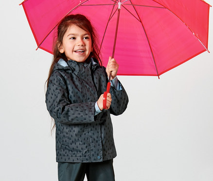 Mädchen hält einen roten Regenschirm und trägt eine Kleinkind-Thermo-Regenjacke, schieferblau Tropfen, und Regenhose.