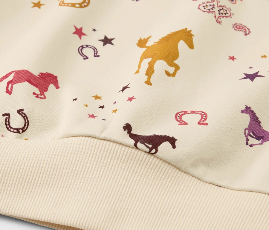Detailansicht eines Kinder-Sweaters mit angerauter Innenseite und Pferde-Alloverprint.