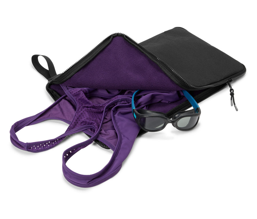 Lila Badebekleidung und Schwimmbrille in einer schwarzen Tasche.