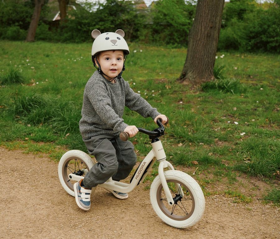 Junge auf einem Laufrad trägt einen HUDORA Kinderhelm, Beary, 44–47 cm.