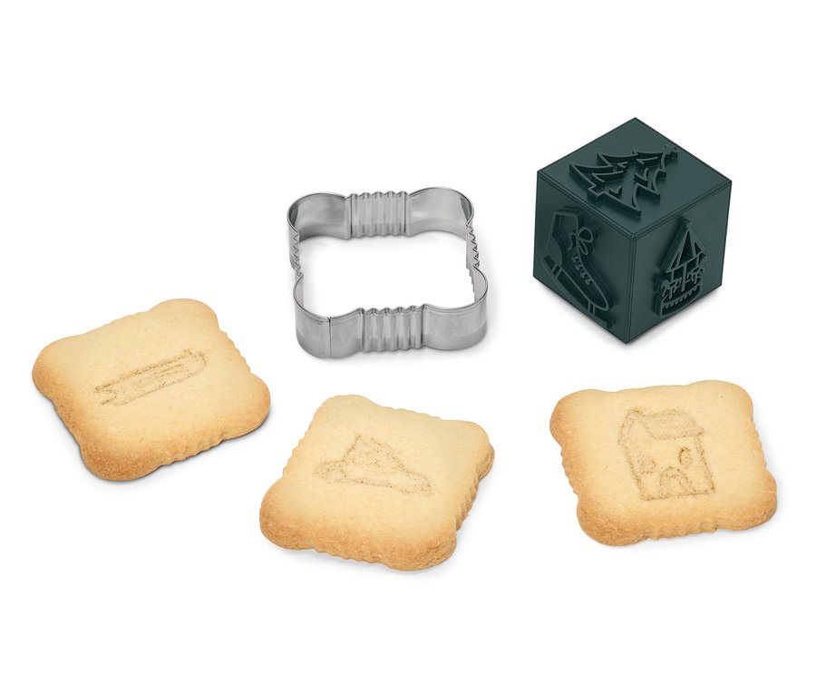 Quadratische Kekse mit Aufdruck von Schlittschuh, Baum und Haus mit Ausstechform und Stempel.