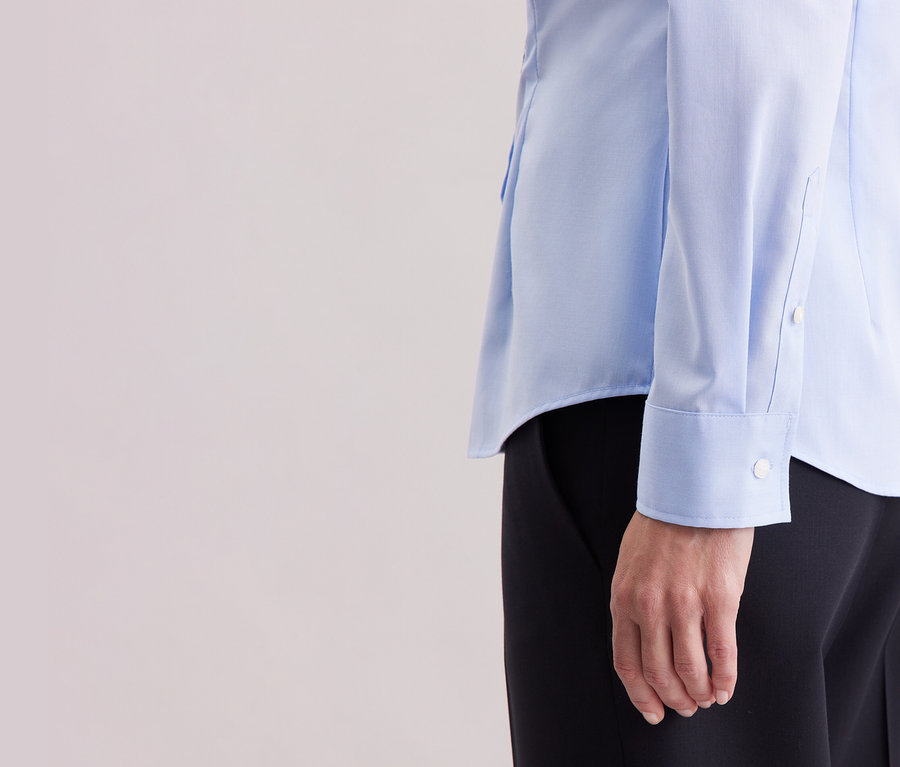 Detailansicht einer Person, die eine hellblaue Seidensticker Bluse Slim Fit non iron trägt.