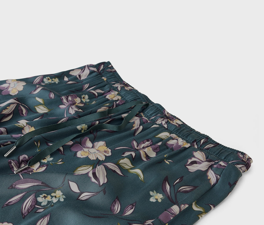 Nahaufnahme einer smaragdgrünen Hose mit Blumenmuster, elastischem Bund und Kordelzug.