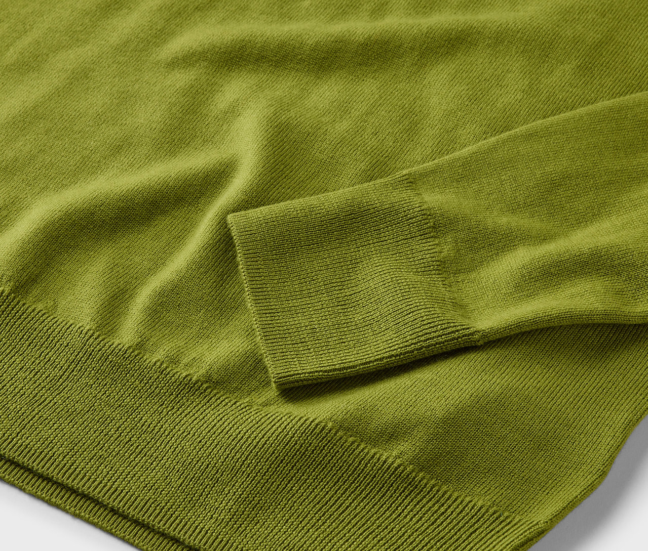 Detailaufnahme eines hellgrünen Merino-Feinstrickpullovers.
