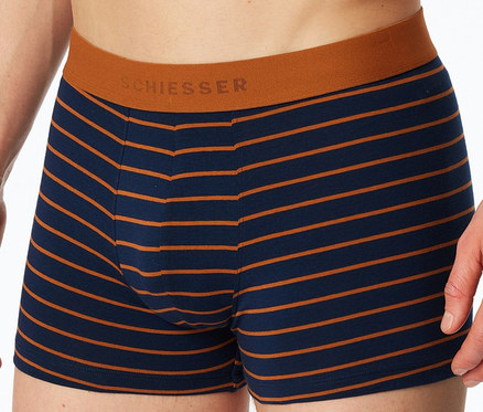 Nahaufnahme einer Person, die einen marineblauen und orange gestreiften SCHIESSER Slipboxer mit orangefarbenem Bund trägt.