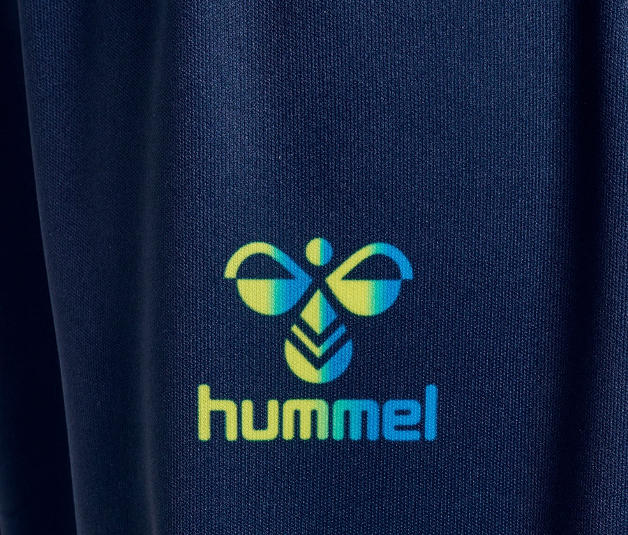 Detailaufnahme des Hummel-Logos auf einem marineblauen Stoff.
