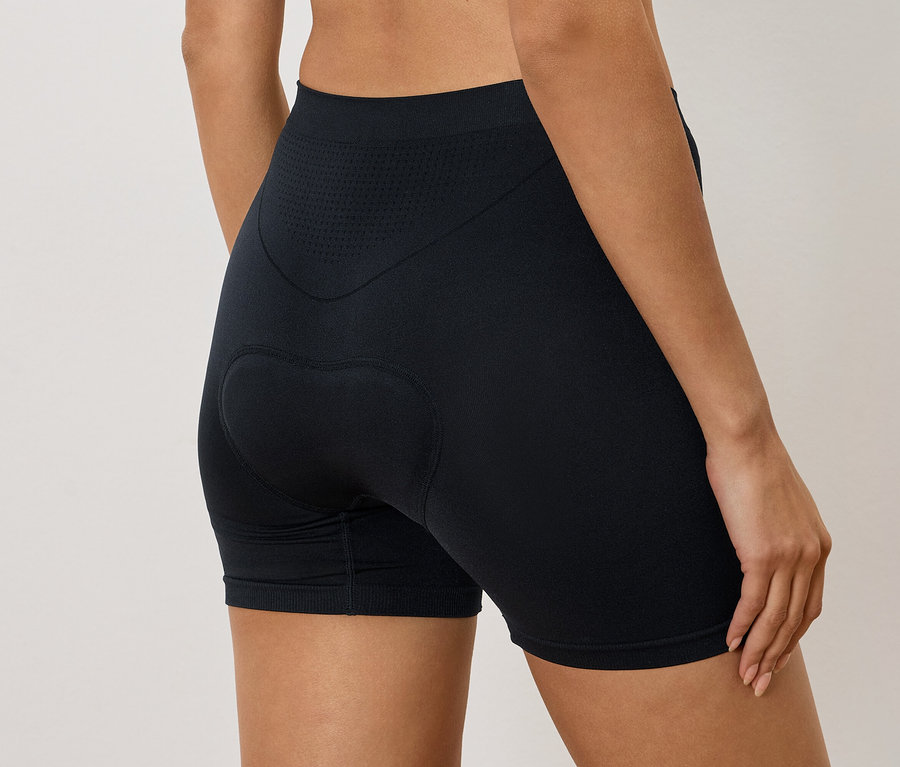 Frau trägt schwarze Radlerhose mit Polsterung am Gesäß, von hinten gesehen.