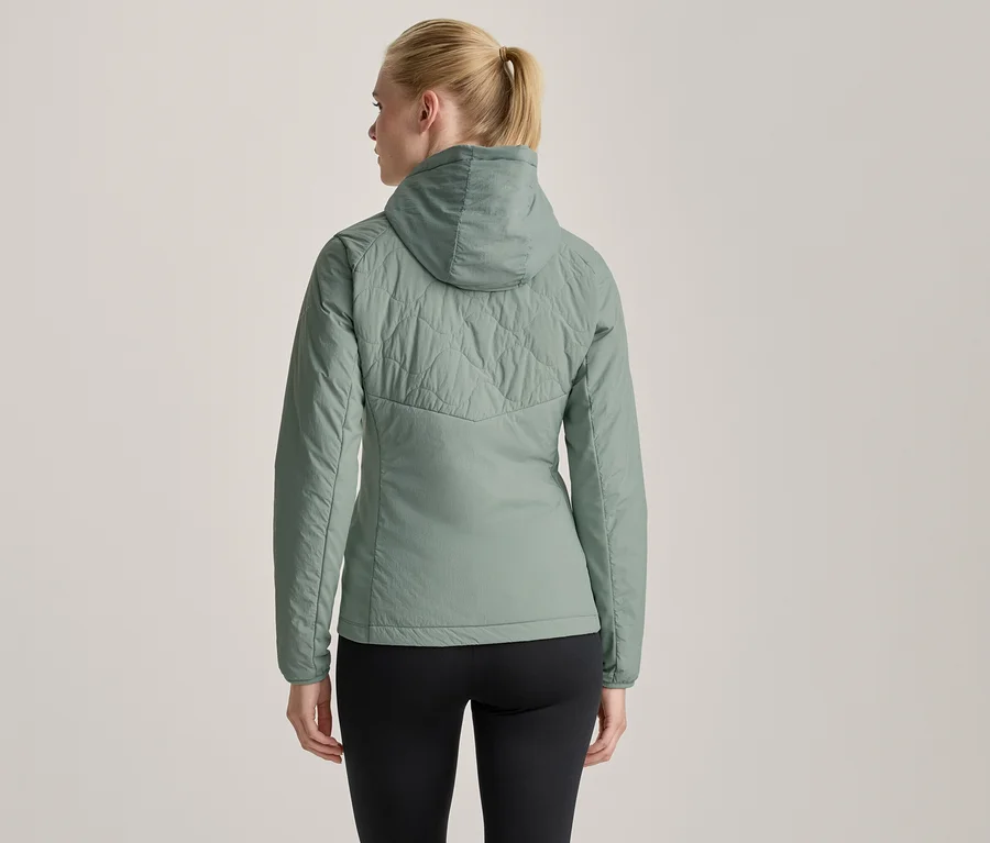 Frau von hinten in hellgrüner Steppjacke mit Kapuze und schwarzen Leggings.