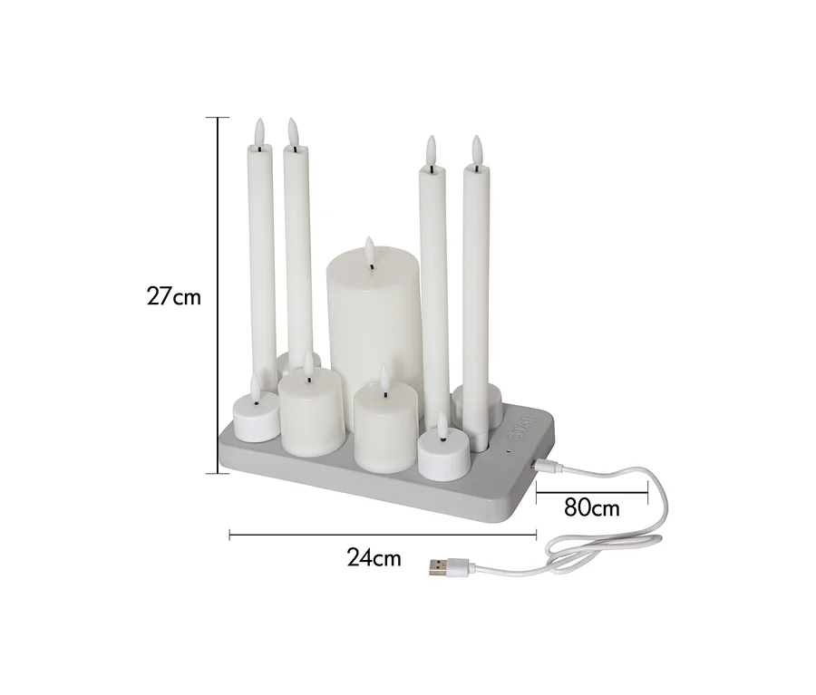 Eine Anordnung von neun weißen LED-Kerzen auf einer grauen rechteckigen Basis, darunter vier hohe, eine dicke und vier Teelicht-Kerzen. Ein 80 cm langes USB-Kabel ist angeschlossen. Die Anordnung ist 27 cm hoch und 24 cm breit.