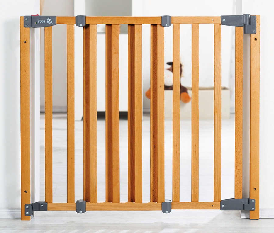 Ein hellbraunes roba Türschutzgitter »Safety Up« aus Holz mit vertikalen Sprossen, in einem weißen Türrahmen montiert.