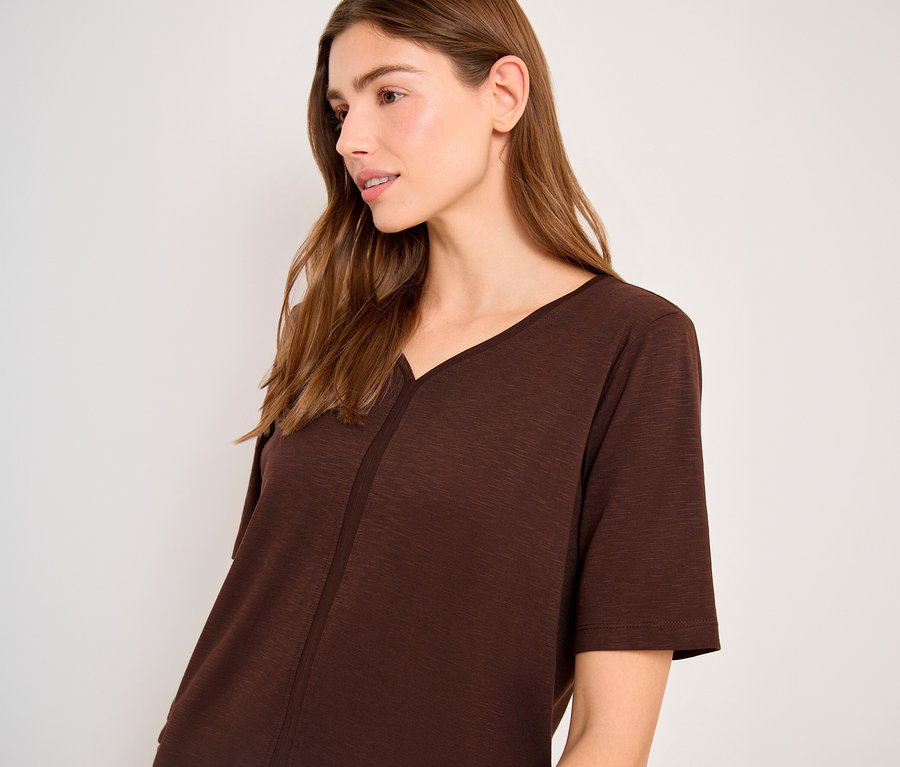 Eine Frau mit langen braunen Haaren trägt ein braunes CECIL Tunika-Shirt mit V-Ausschnitt, kurzen Ärmeln und einer Naht vorne.