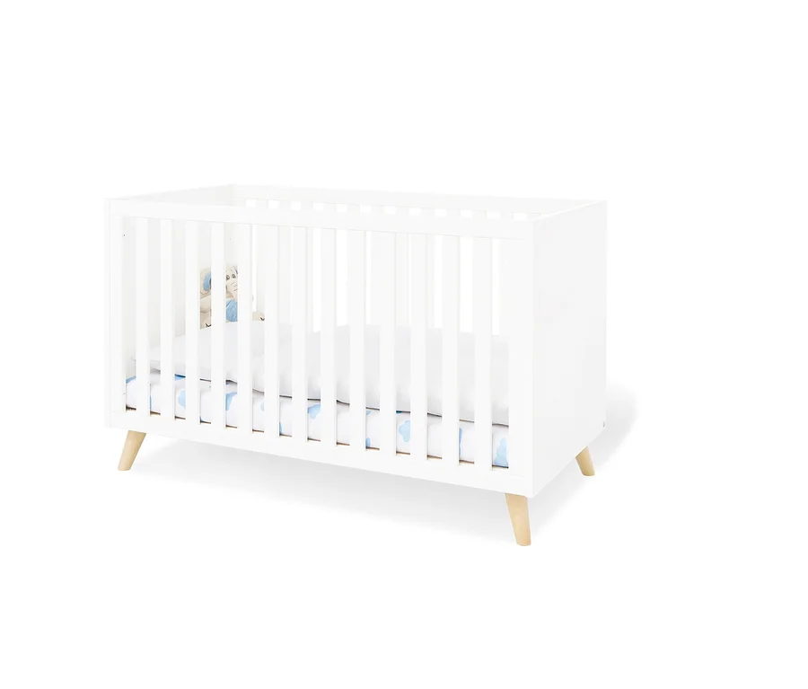 Weißes Pinolino Babybett »Move« mit weißer Unterlage und Elefantenspielzeug.