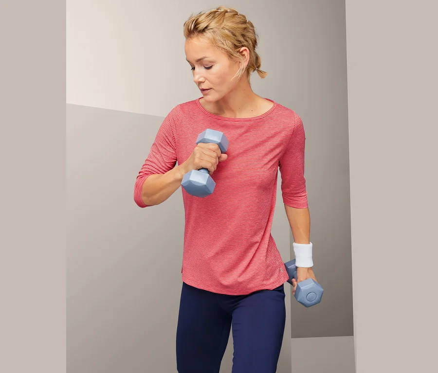 Frau trainiert mit blauen Hanteln und trägt ein Funktionsshirt.
