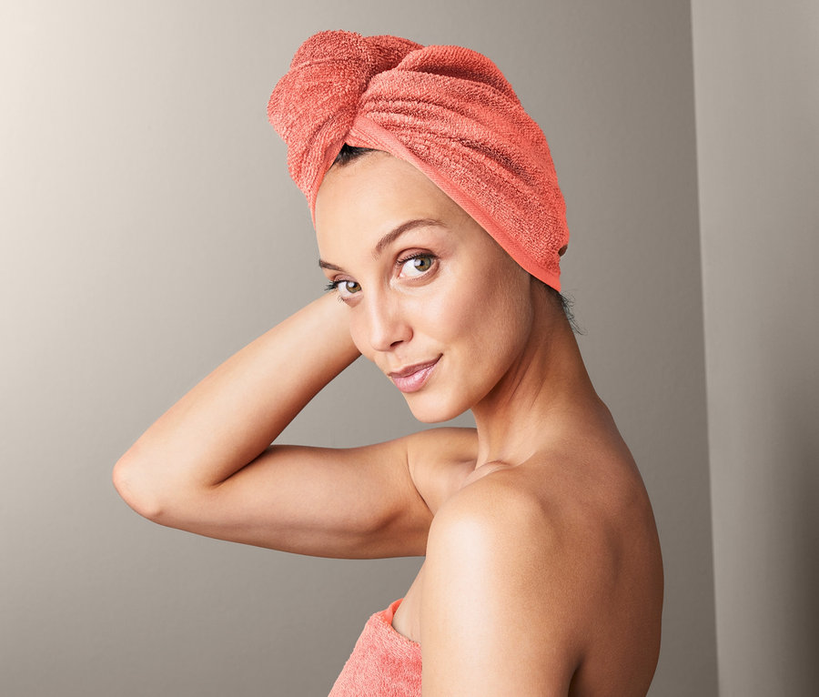 Frau mit Turban-Handtuch auf dem Kopf und einem Handtuch um den Körper gewickelt.