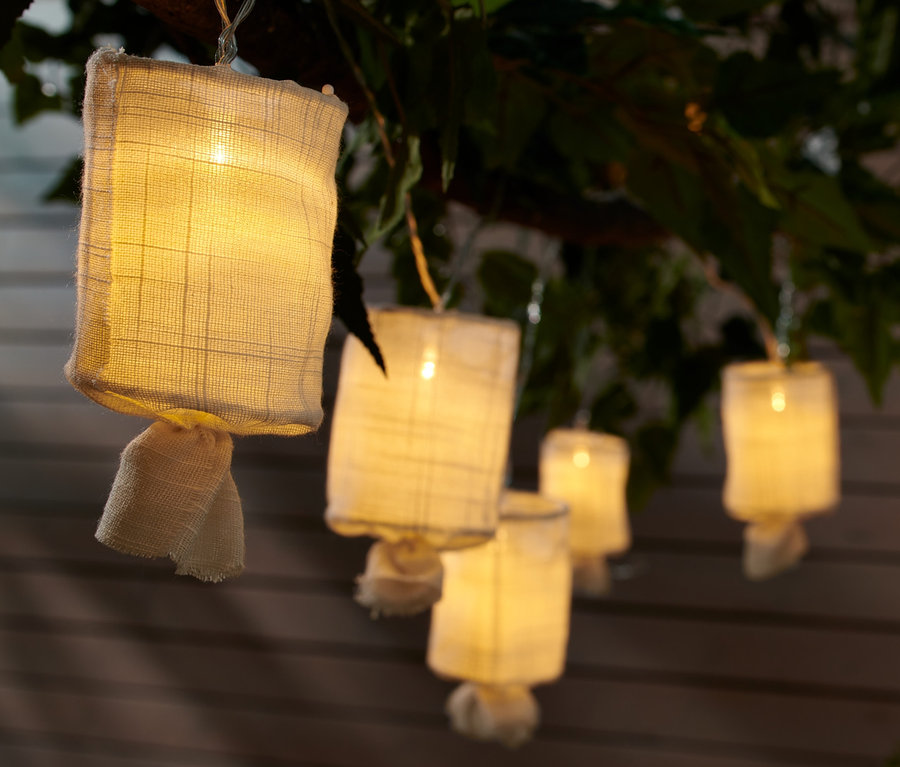 LED-Lichterkette mit Stoffschirmen hängt an einem Ast.