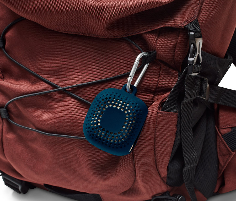 Ein brauner Rucksack mit einem Karabiner, an dem eine blaue Hülle für ein Outdoor-Handtuch hängt.