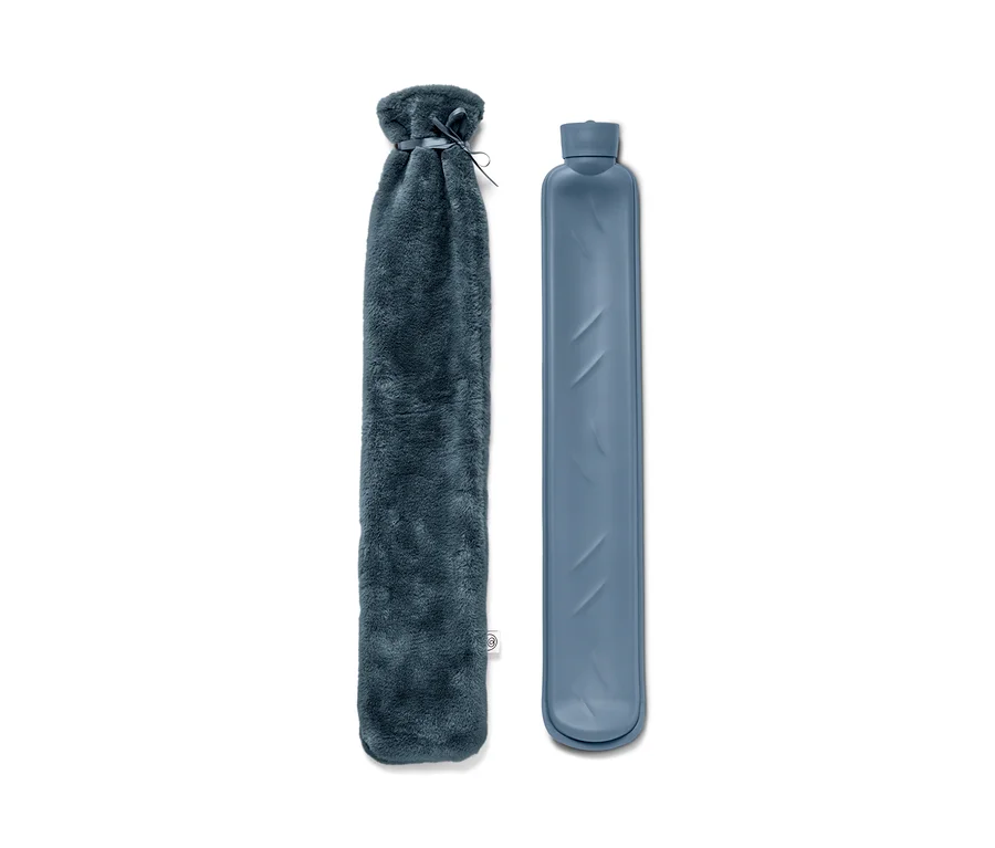 Eine Schlauch-Wärmflasche mit Plüschbezug und eine Schlauch-Wärmflasche ohne Bezug liegen nebeneinander auf einem weißen Hintergrund.