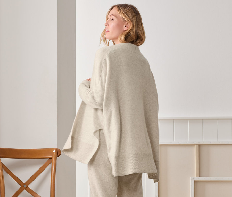 Frau posiert von hinten in Cashmere-Strickjacke, Jogginghose und Socken.