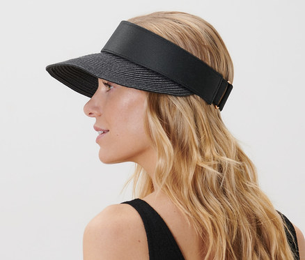 Frau mit blonden Haaren trägt einen schwarzen Sonnenvisor.
