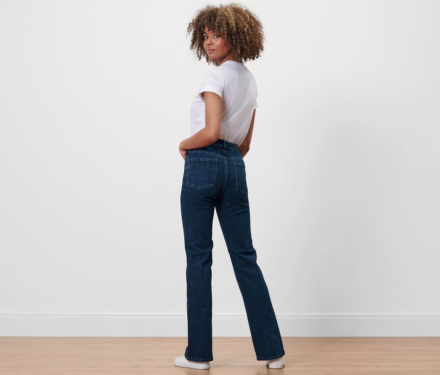 Frau blickt über die Schulter und posiert in Bootcut-Denim »Fit Lou« und weißem T-Shirt.