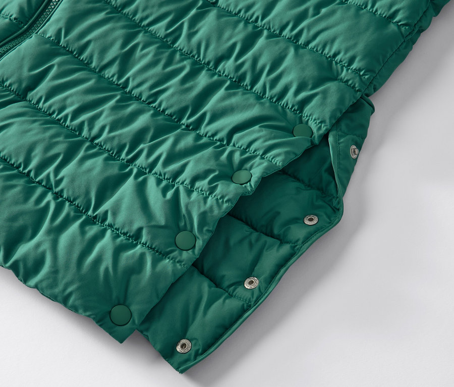 Detailansicht eines grünen Steppmantels mit Kapuze und Druckknöpfen.