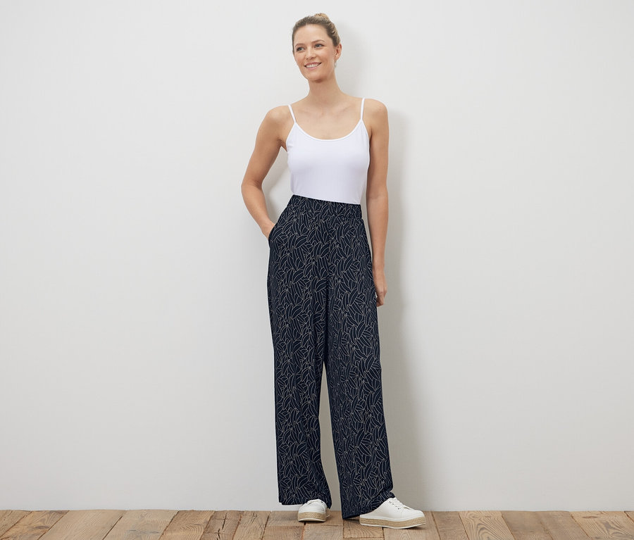 Frau posiert in dunkelblau-cremeweiß bedruckter Palazzohose.