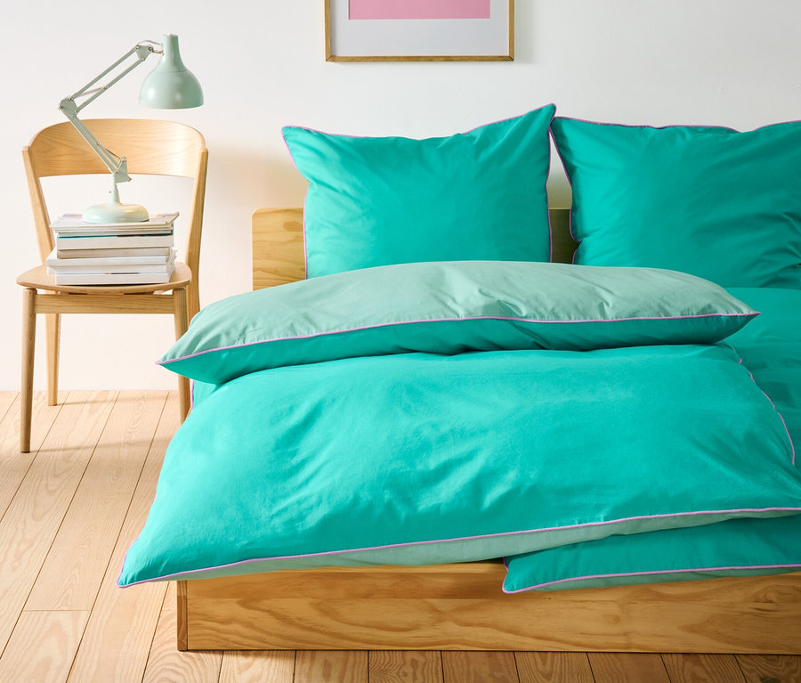 Auf einem Bett liegen drei Renforcé-Bettwäsche-Sets in Normalgröße und ein Set in Übergröße.