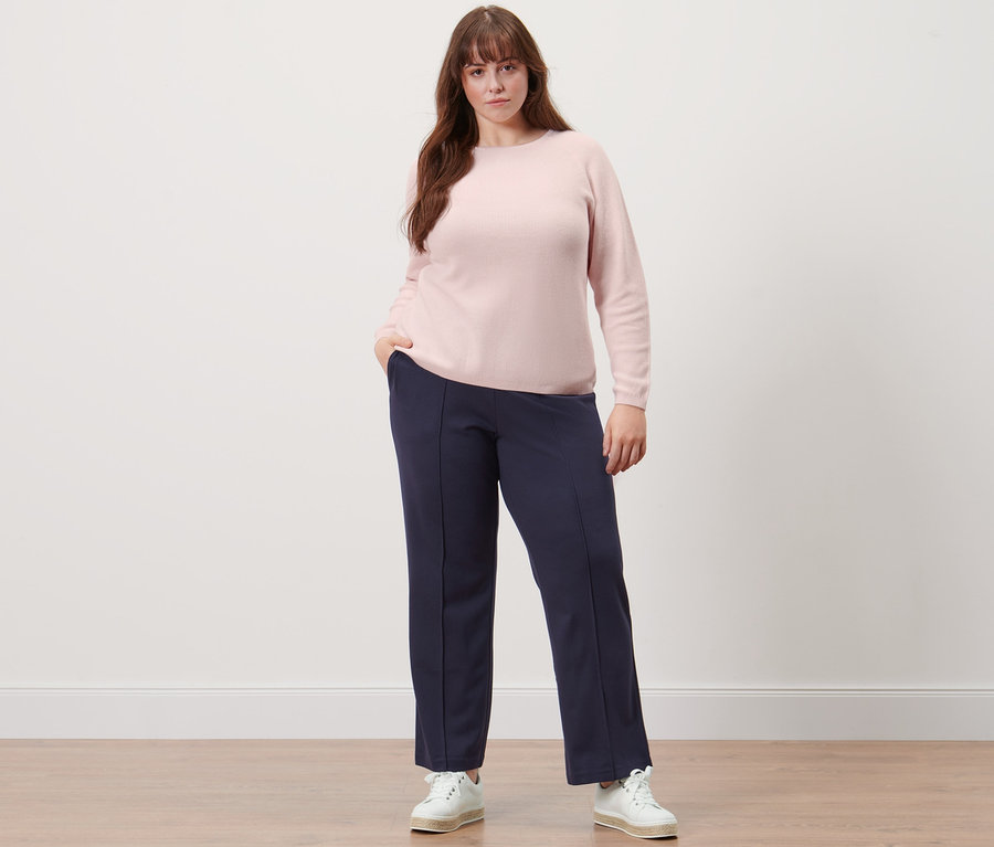 Frau posiert in Strickpullover und dunkelblauer Jerseyhose mit Biese.