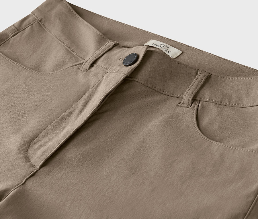 Detailaufnahme einer beigen Hose mit Knopf.