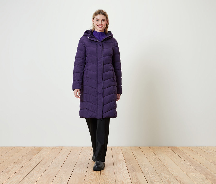 Frau trägt einen langen, lila Steppmantel mit Kapuze.