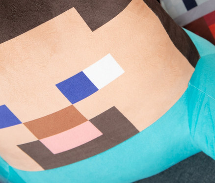 Detailaufnahme von drei Minecraft-Kissen auf einem grauen Sofa. Das vorderste Kissen ist Steve.