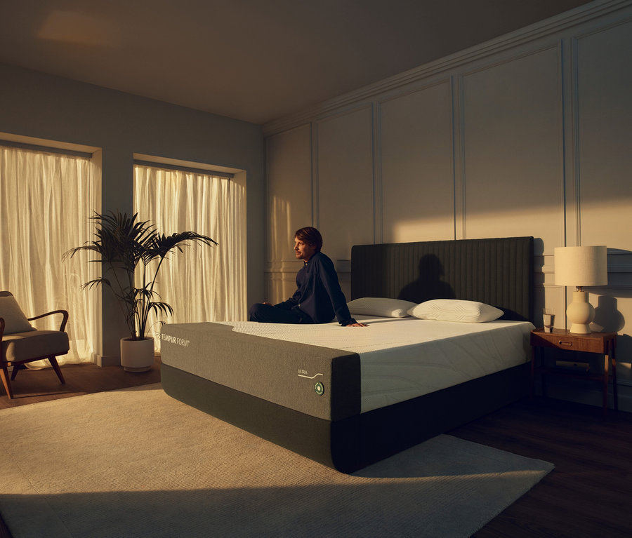 Mann sitzt auf TEMPUR Form™ Plus Matratze Medium im Schlafzimmer.