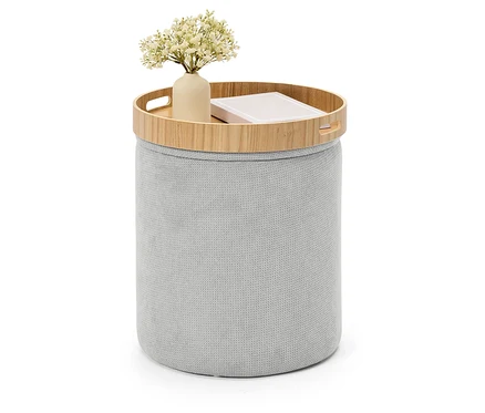Grauer Strickhocker mit Holztablett, darauf eine Vase mit Blumen und ein Buch.