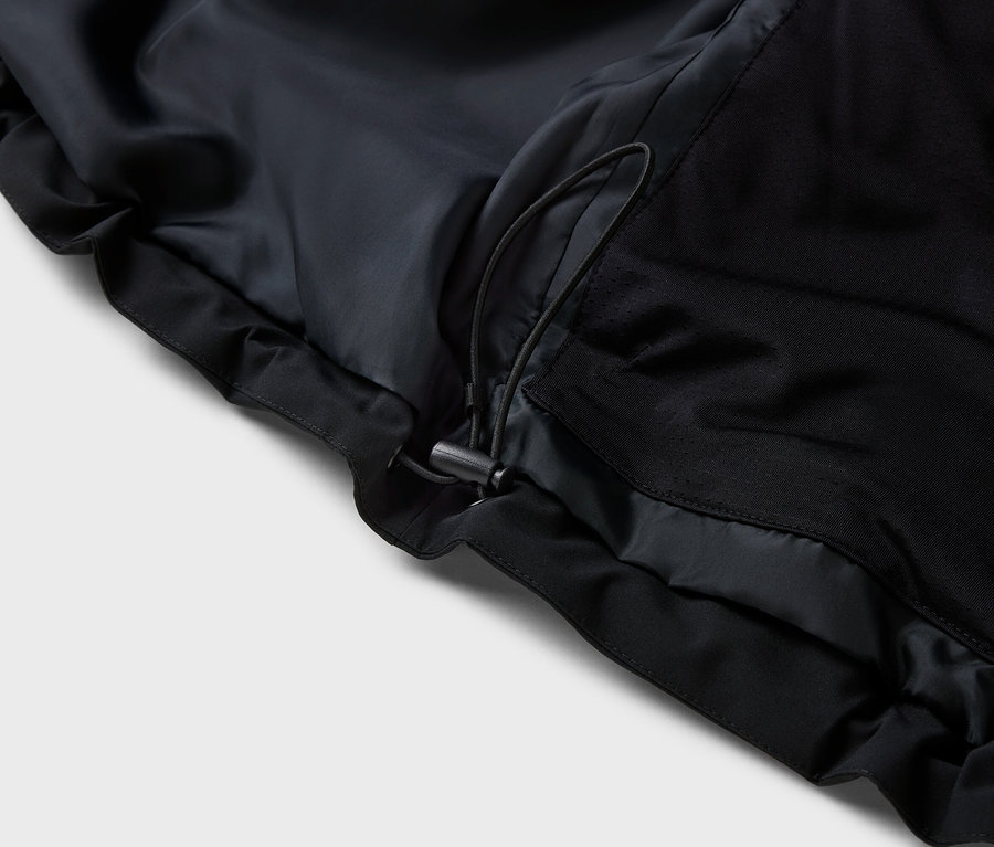 Detailaufnahme einer schwarzen Jacke mit Kordelzug.