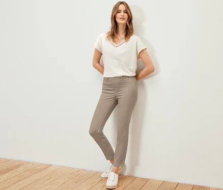 Frau posiert in 7/8-Treggings, T-Shirt und Turnschuhen.
